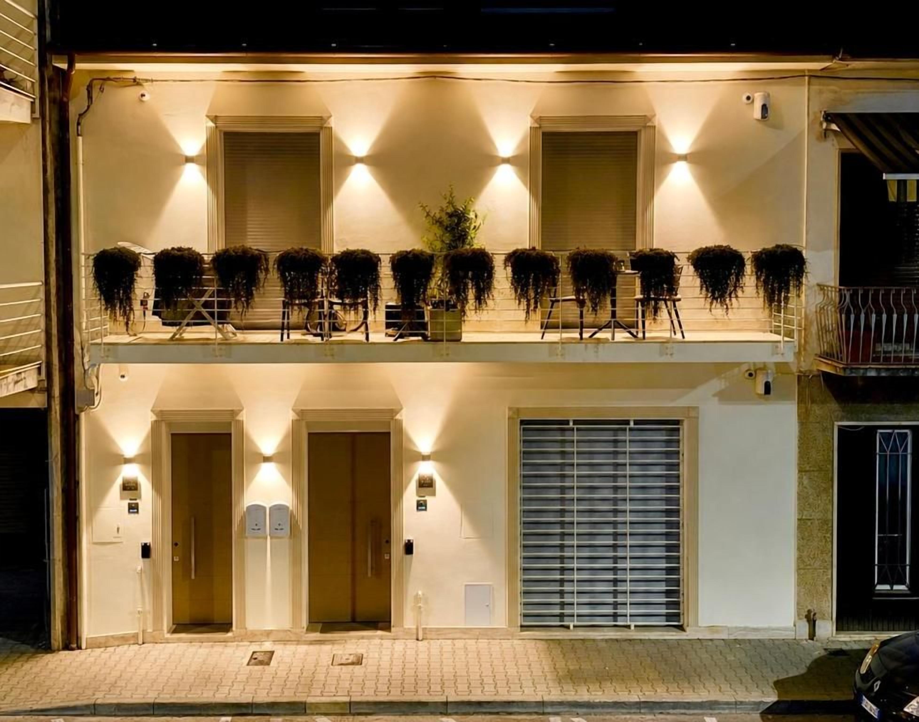 Un edificio de dos pisos con balcón, puerta de garaje y un juego de puertas dobles.