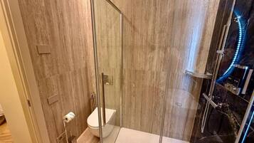 A modern bathroom with a glass-enclosed shower, a toilet, and a bidet.