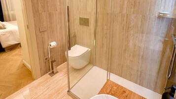Un baño moderno con ducha envuelta en vidrio, inodoro blanco y bañera de mármol.