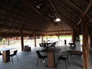 An open-air dining area with tables and chairs, a thatched roof, and a view of the outdoors. - Ecohotel Payara Puerto Gaitán (Puerto Gaitán)