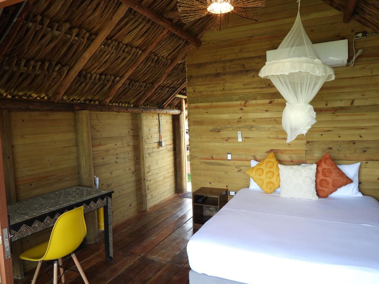Ein Zimmer mit Holzboden, einem Bett, einem Schreibtisch und einem gelben Stuhl.