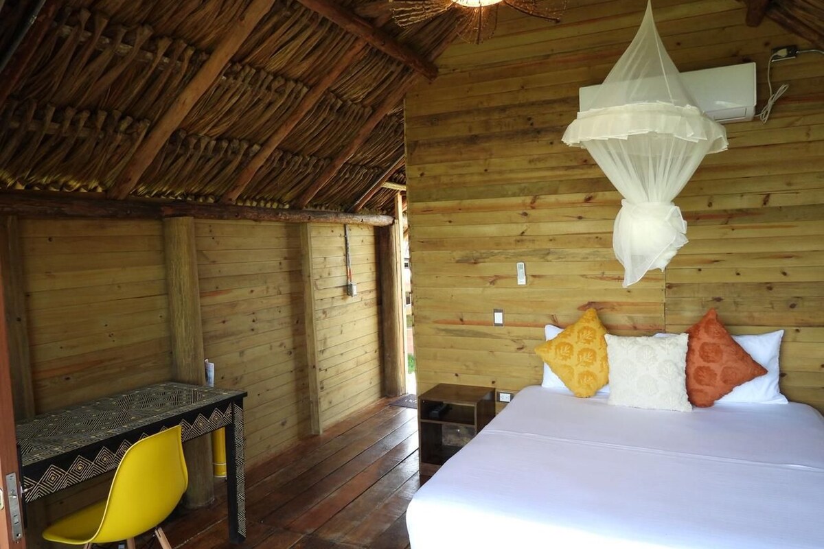 A wooden room with a bed, a desk, and a yellow chair.