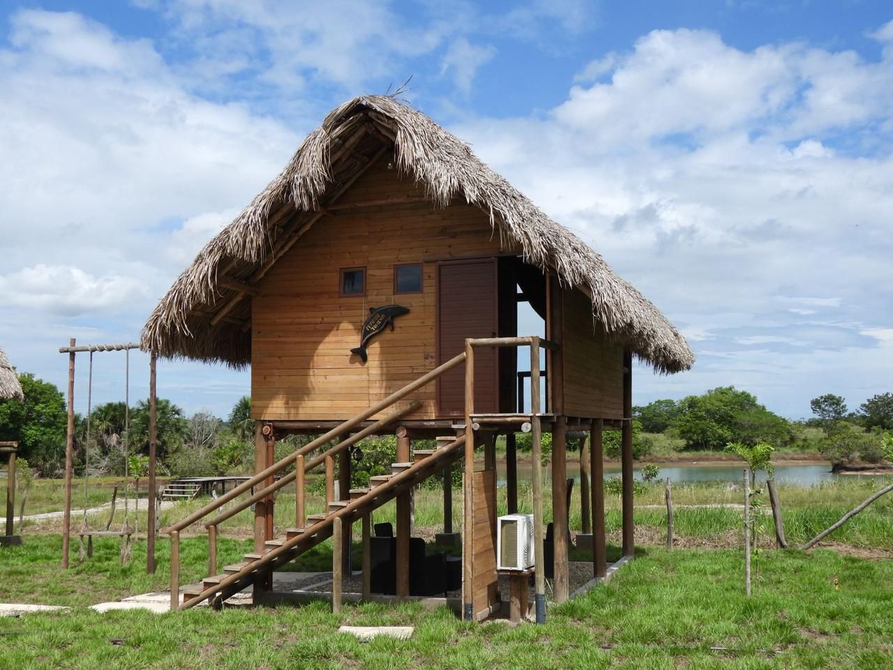 A wooden structure with a thatched roof, a staircase leading to an upper level, and a small window.