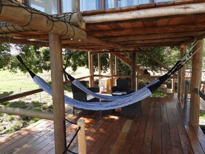 A hammock suspended between wooden beams on a wooden deck.