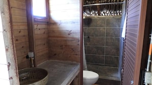 Un baño de cabaña de madera con inodoro, ducha y suelo de madera.