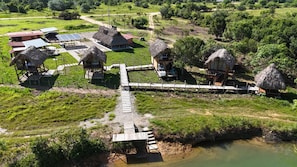 A rural accommodation with thatched-roof huts, a wooden bridge, and a solar power setup. - Ecohotel Payara Puerto Gaitán (Puerto Gaitán)