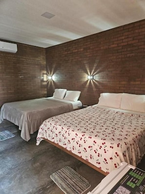 Une chambre d’hôtel avec deux lits, un mur en briques et deux lampes fixées au mur.