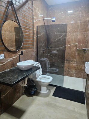 Un baño con inodoro blanco, lavabo y zona de ducha.
