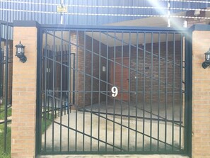 A gated entrance with a number '9' on the gate, a brick wall, and a metal gate. - Hoteis Online  (Boa Vista)