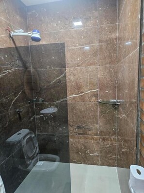 A bathroom with a toilet, a shower, and a glass-enclosed shower area. - Hoteis Online  (Boa Vista)