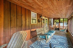 Una cabana de fusta amb un porxo, una panxa de rata, una cadira d'oscil·lació i una catifes amb dibuixos.