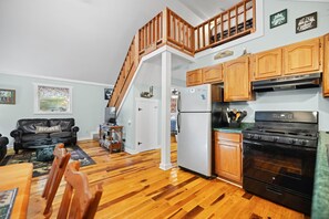 A spacious living area with a wooden staircase, a kitchen with wooden cabinets and appliances, and a dining area with a table and chairs. - Gorge-Us Getaway: A Cozy Retreat for Family and Friends (Zoe)