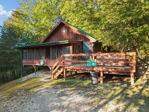 Eine Holzhütte mit Veranda und Bank, umgeben von Bäumen.