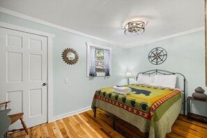 A bedroom with a bed, a window with curtains, a wall clock, a compass decoration, and a wooden floor. - Gorge-Us Getaway: A Cozy Retreat for Family and Friends (Zoe)