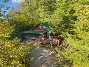 A cabin with a green roof, surrounded by dense forest. - Gorge-Us Getaway: A Cozy Retreat for Family and Friends (Zoe)