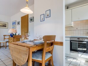 A dining area with a wooden table set for four, chairs, a lamp, and framed pictures on the wall. - 1 in the House "trischen" (St. Peter-Ording)