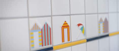 Parede revestida de azulejos com uma fileira de ícones estilizados de edifícios.