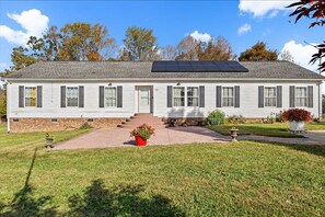 A single-story house with a brick foundation, a front door, and a small front yard with a pathway leading to the door. - Large Spacious Home: Close to Hyco and Mayo Lake (Timberlake)