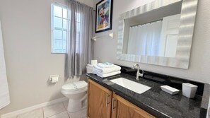 A bathroom with a toilet, sink, and mirror. - 4 BD/ 3 BA/ Rolling Hills Estates (7952 HE) (Kissimmee)