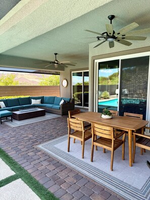 Un patio al aire libre con una mesa de comedor, sillas, un sofá y un ventilador de techo.