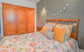 A bedroom with a large wooden wardrobe, a bed with floral bedding, and a wall-mounted light fixture. - The House of Viennes (SAINT ANDRE LES VERGERS)
