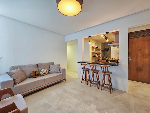 A modern living room with a sofa, a coffee table, and a bar area with stools. - Barra - Salvador (Salvador)