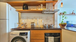 Cozinha compacta com máquina de lavar, lava-louças, fogão e pia.