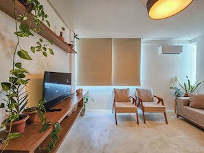 A modern living room with a flat-screen TV, two armchairs, a sofa, and potted plants. - Barra - Salvador (Salvador)