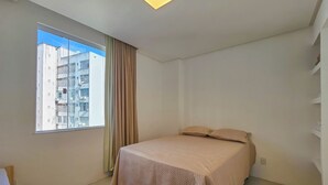 A bedroom with a bed, a window, and a ceiling light. - Barra - Salvador (Salvador)