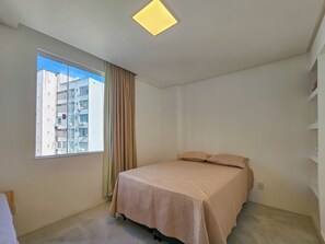 Ein Schlafzimmer mit Bett, Fenster und Deckenleuchte.