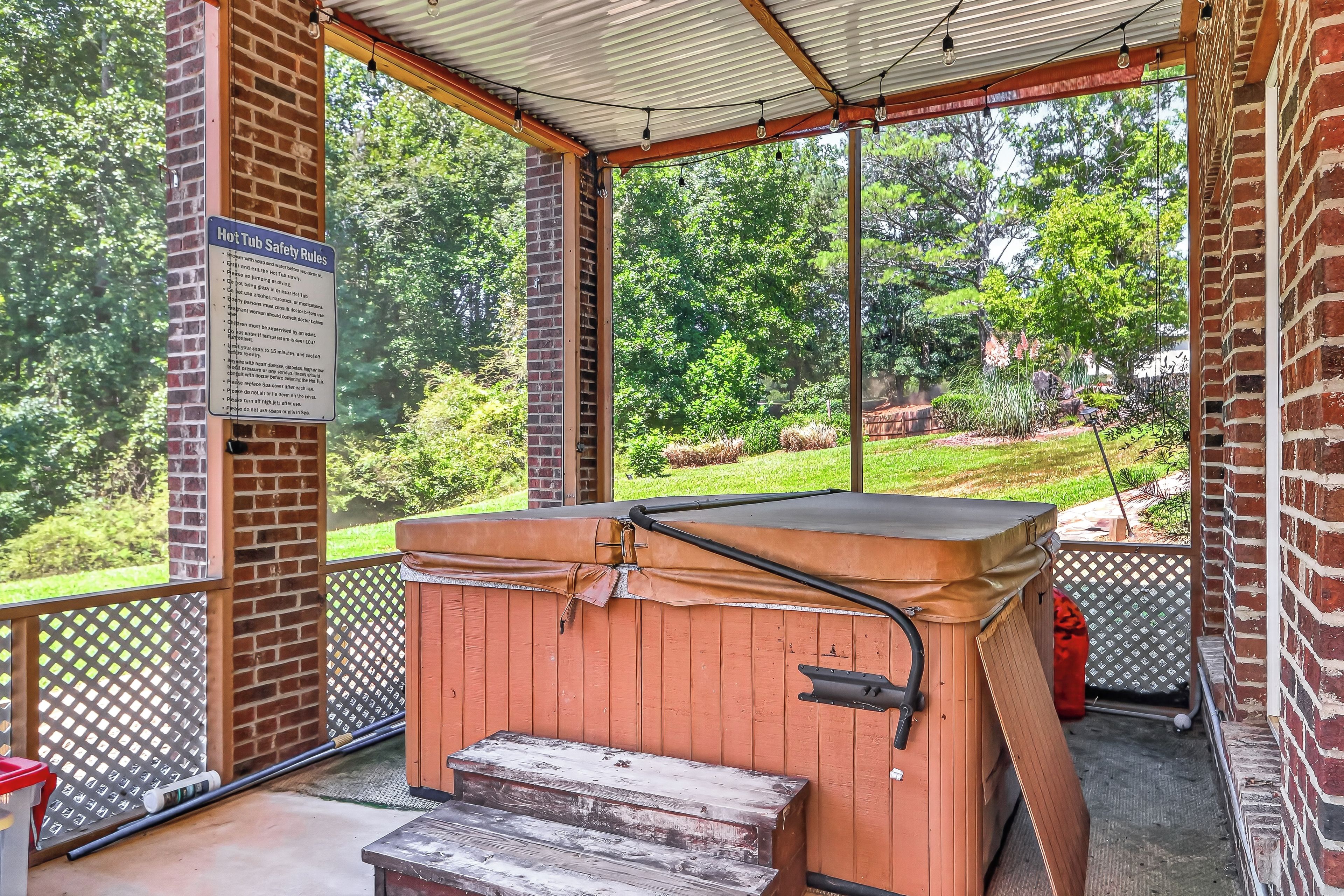 A covered outdoor hot tub area with a wooden bench and steps leading up to it.
