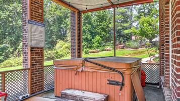 A covered outdoor hot tub area with a wooden bench and steps leading up to it.