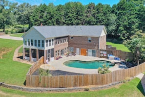 Une maison à deux étages avec une piscine, une cour clôturée et une terrasse en bois.