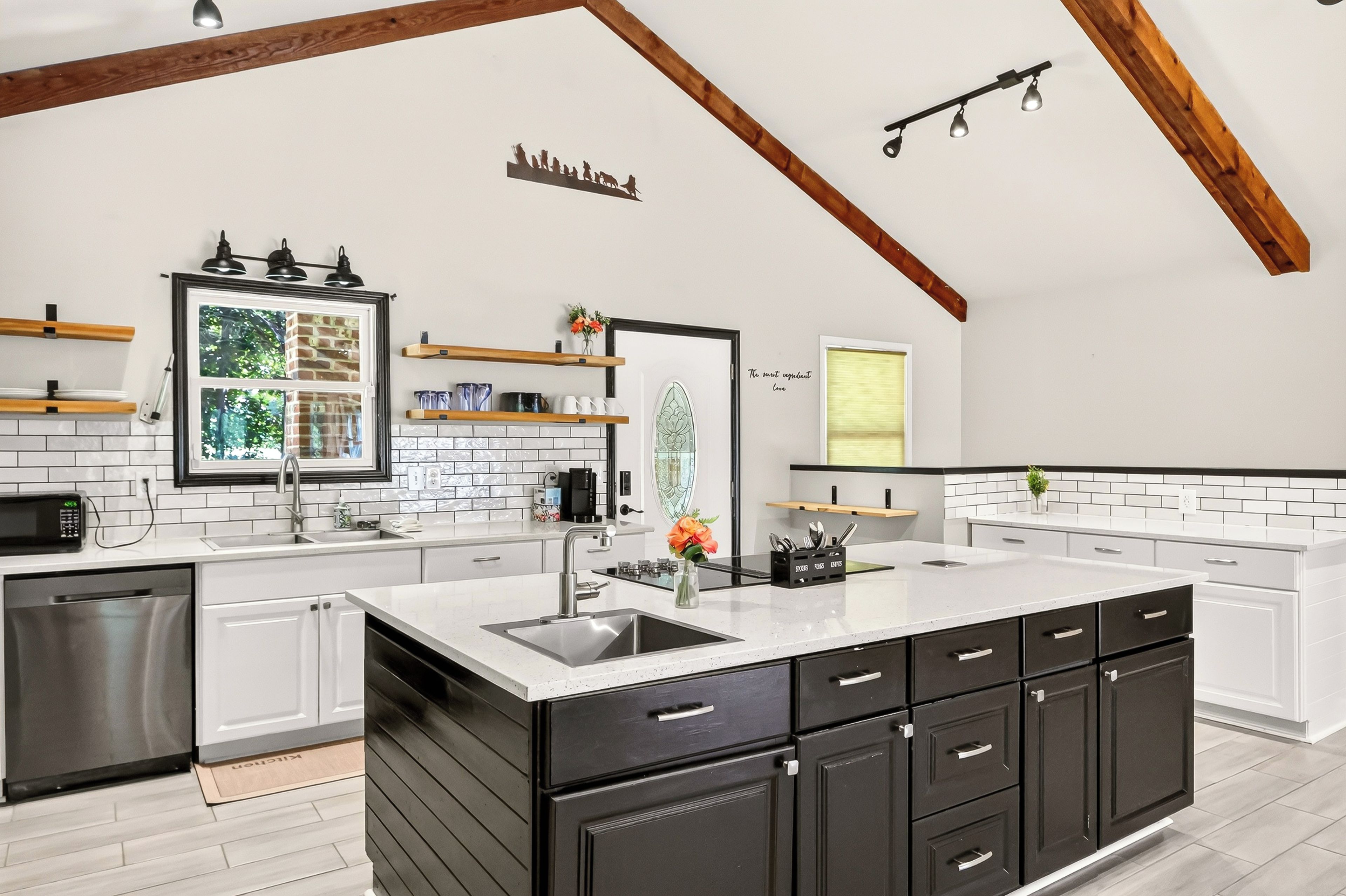 A modern kitchen with white cabinetry, a large island, and a black countertop.