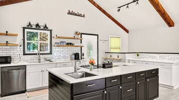 A modern kitchen with white cabinetry, a large island, and a black countertop.