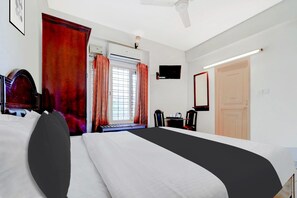 Una habitación de hotel con cama, escritorio, silla, televisor y puerta.