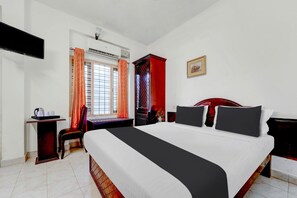 Habitación de hotel con cama, escritorio, silla y ventana con cortinas.