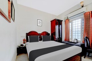 Habitación de hotel con una cama grande, un escritorio con silla, una ventana con cortinas y un equipo de aire acondicionado de pared.