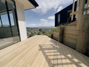 Un terrazzo in legno con vista su una zona residenziale e un edificio moderno.