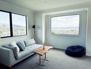 Un soggiorno moderno con un divano grigio, un tavolino in legno e un pouf blu.