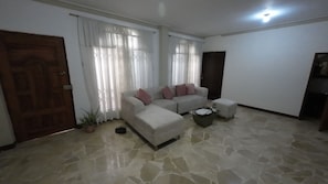 A living room with a sofa set, a coffee table, and a potted plant.