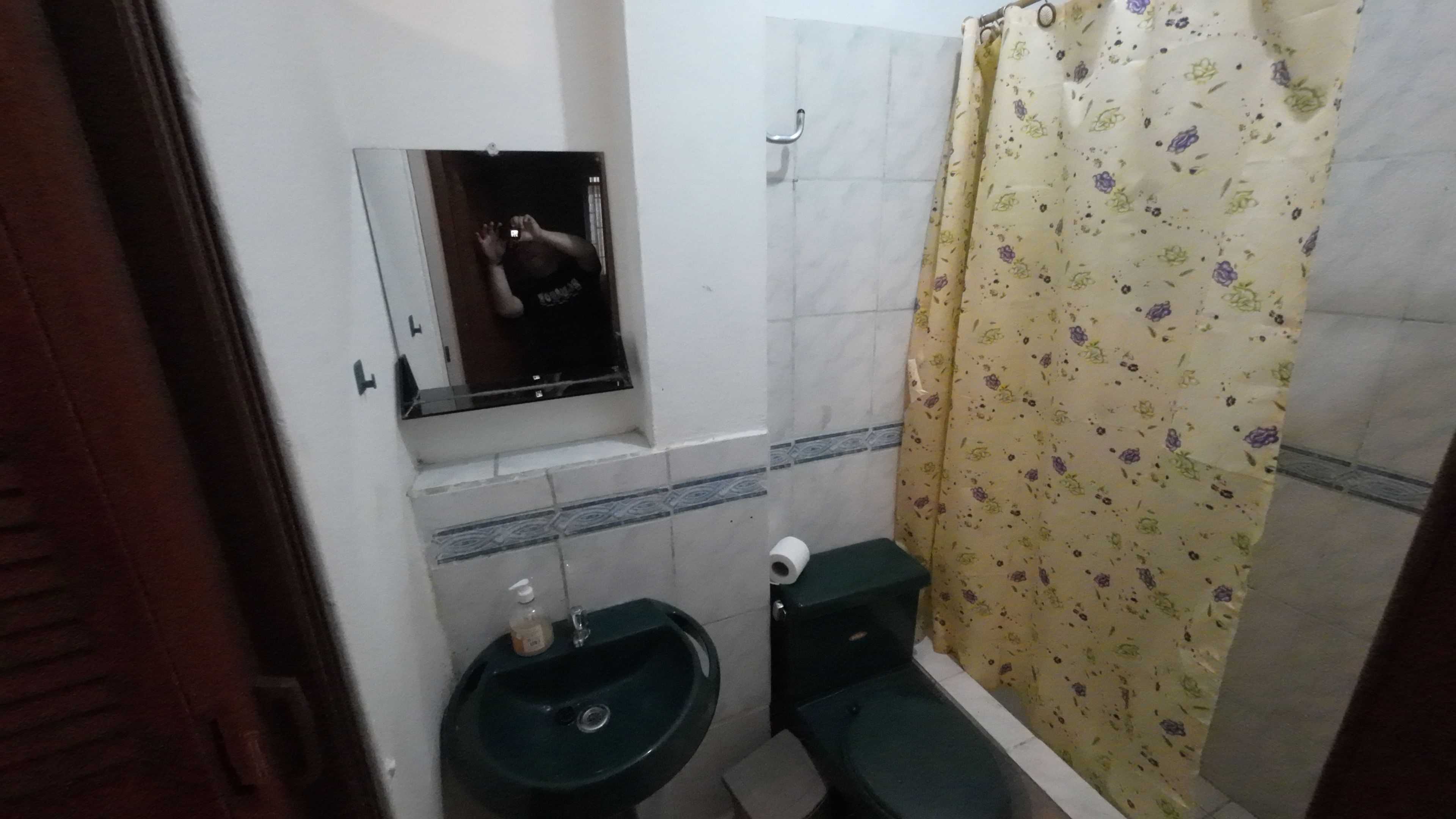 Et lille badeværelse med vask, toilet og et spejl over vasken.