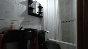Un baño con un lavabo negro, inodoro y zona de ducha.
