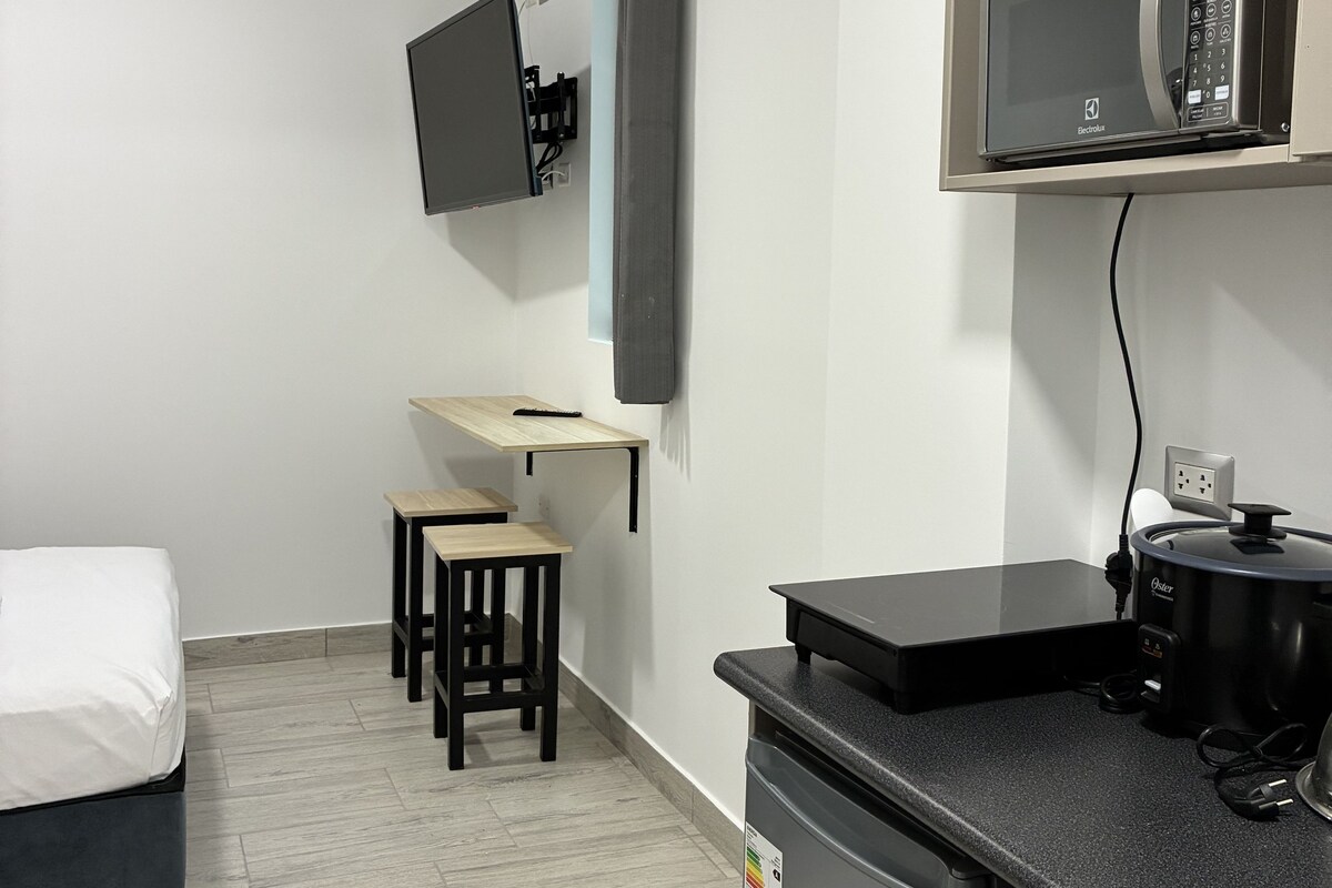 A compact kitchenette with a microwave, a small refrigerator, and a countertop.