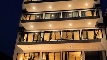 A multi-story hotel with a modern design, featuring balconies on each floor and a well-lit entrance.