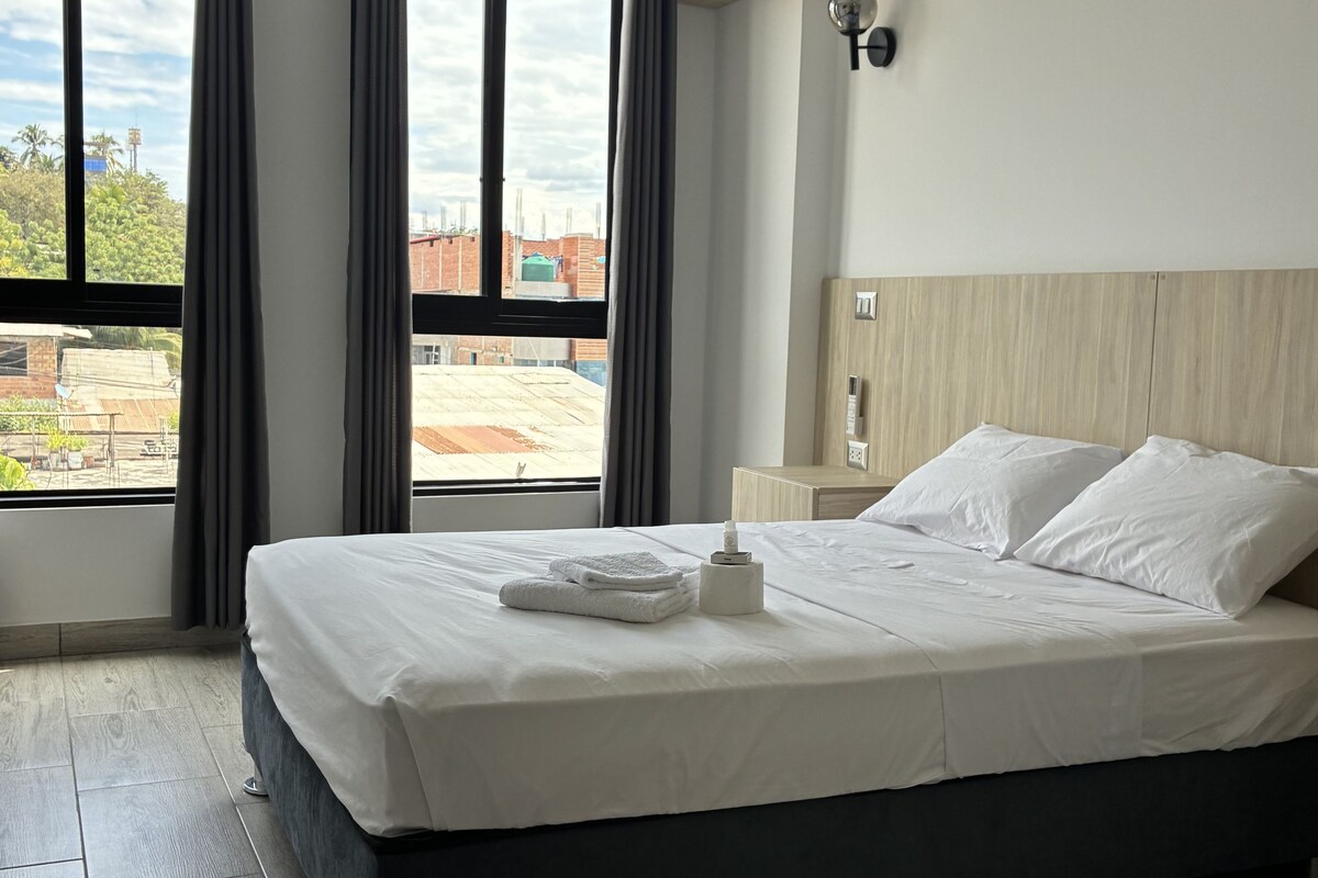 A hotel room with a large bed, a view of the cityscape, and a modern design.