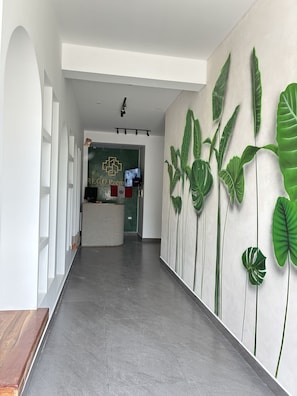 A reception area with a green wall, a reception desk, and a wall with large green leaves. - Rego Premium Apart Hotel (Bagua Grande)