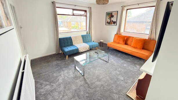 Ein Wohnzimmer mit einer Couch, einem Couchtisch und einem Fernseher.