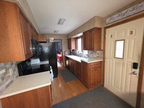 A kitchen with wooden cabinets, a black refrigerator, a countertop, and a door with a window.