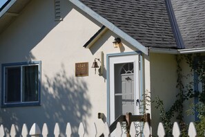 Ein Haus mit weißer Fassade, einer blauen Tür und einem Schild mit der Aufschrift '4345 BLUEBELL COTTAGE'.